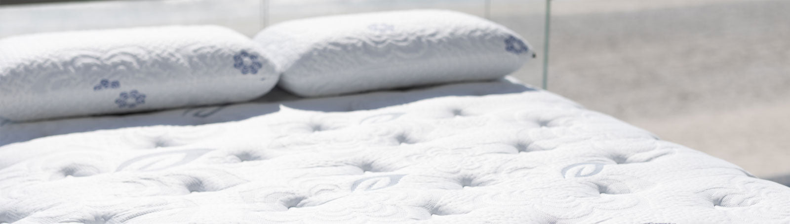 Close-up of the PranaSleep Asha mattress surface featuring plush tufted quilting and matching pillows, highlighting the collection's luxurious all-latex craftsmanship and refined comfort.