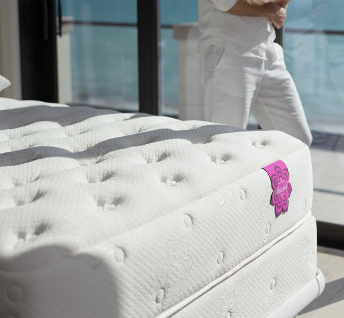 Close-up of the PranaSleep Dharma mattress showcasing its deeply tufted quilted surface and premium craftsmanship in a bright, oceanfront setting, emphasizing luxurious comfort and supportive sleep.