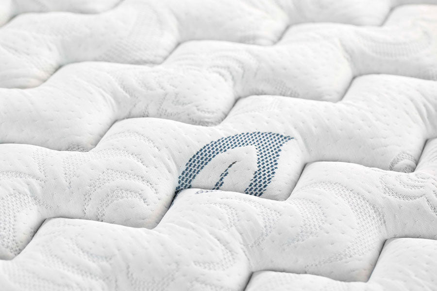Close-up detail of the PranaSleep Asha mattress surface featuring plush, pillowy quilting with a subtle blue embroidered accent, highlighting the collection's luxurious all-latex comfort and refined craftsmanship.