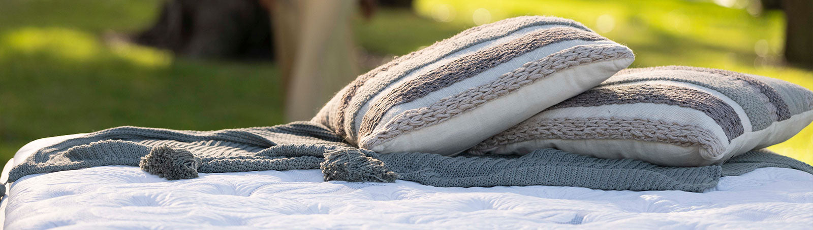 Two striped pillows on a blanket with a blurred outdoor background